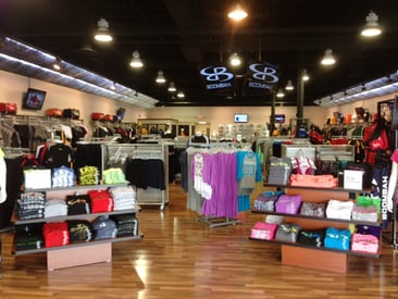 Store displaying 3-tier rectangular tables along with clothing racks