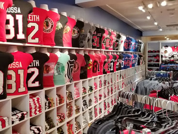 Store displaying mannequins and cubes with branded sports t-shirts