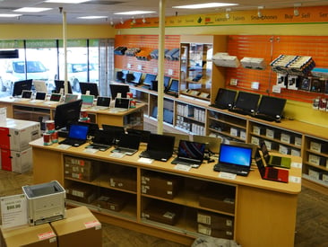 Store displaying electronics section with multiple laptops on countertop displays