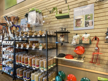 Store showing wire grid displays with wind chimes, bird seed, and feeders
